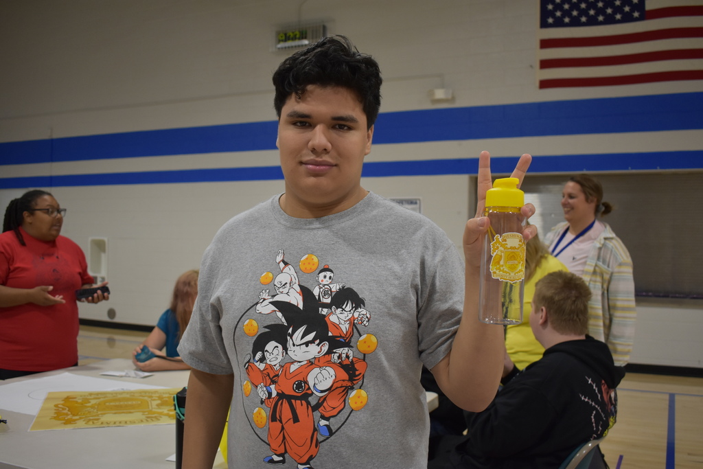 A student holding up a peace sign with his new water bottle