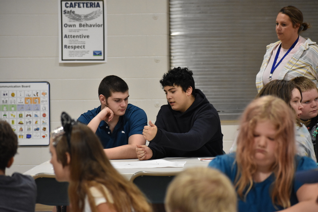 Two students chatting with each other in the back ground at their table