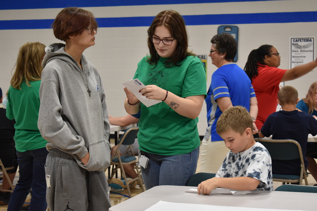 A teacher assistant adn two students from the same house checking out their envelopes for puzzle pieces