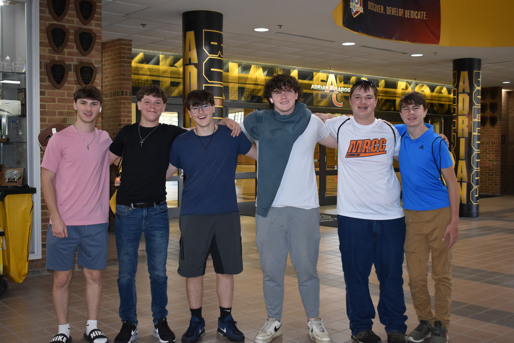 Six students posing together for a photo and smiling at the camera inside an athletic facility