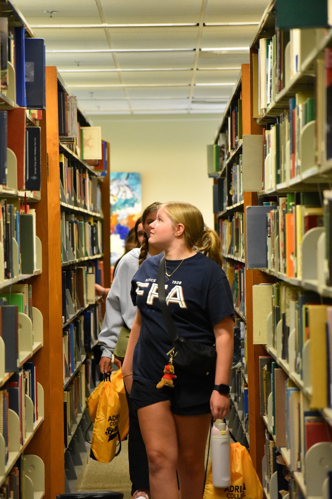 Students walking toward the camera in between book rows at the library