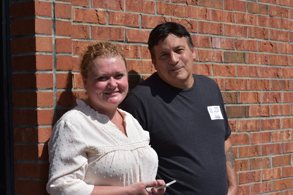 Holly and Mario DiPippo who spoke to students posing for a photo while standing outside against a wall