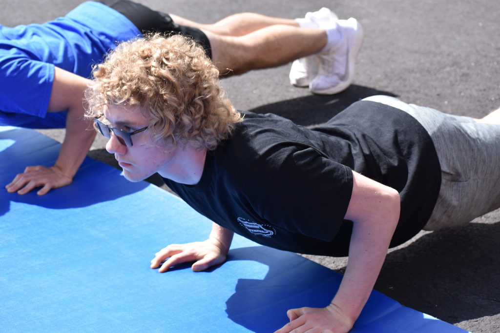 A student completing a pushup on a mat outside