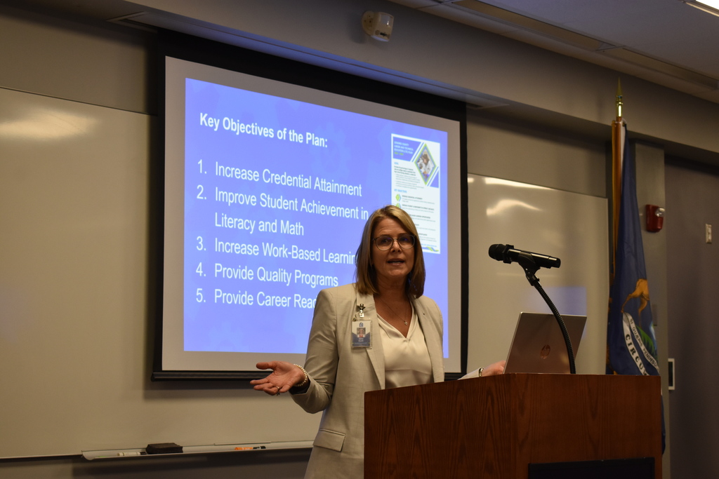 Assistant Superintendent Jenny Heath at the podium with the TECH Center logo on it in a classroom setting.