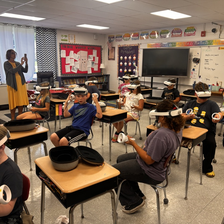 students sit in a classroom with VR headsets on