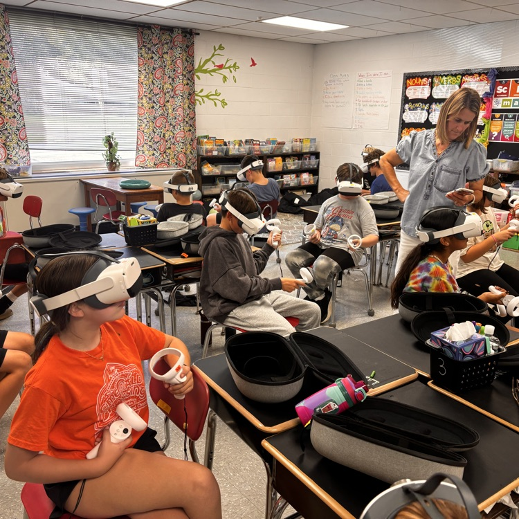 Students sit in a classroom with VR headsets on