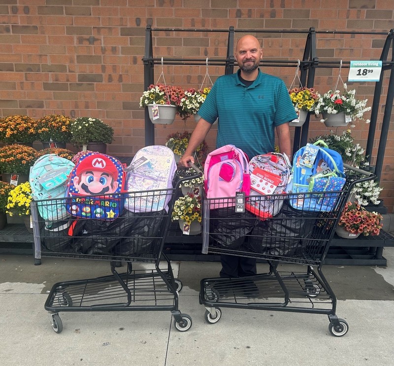 Chris Howard with the LISD standing in front of carts filled with backpacks