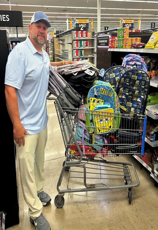 Matt Randall with the Department of Corrections standing with backpacks