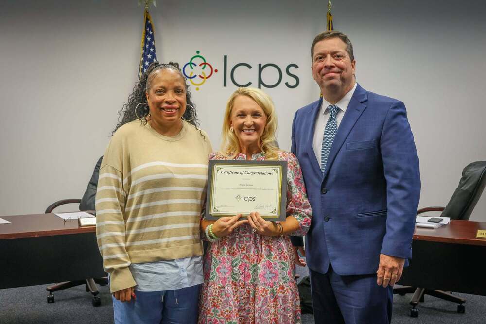 Three adults stand in front of LCPS logo