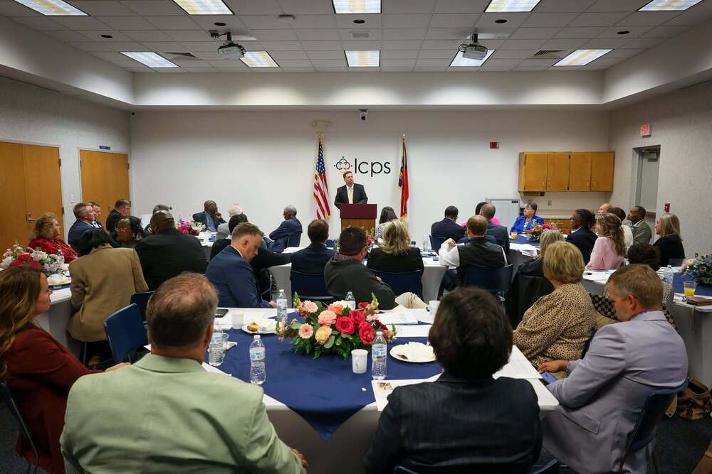 A group of people listen to a man speaking at the podium in front