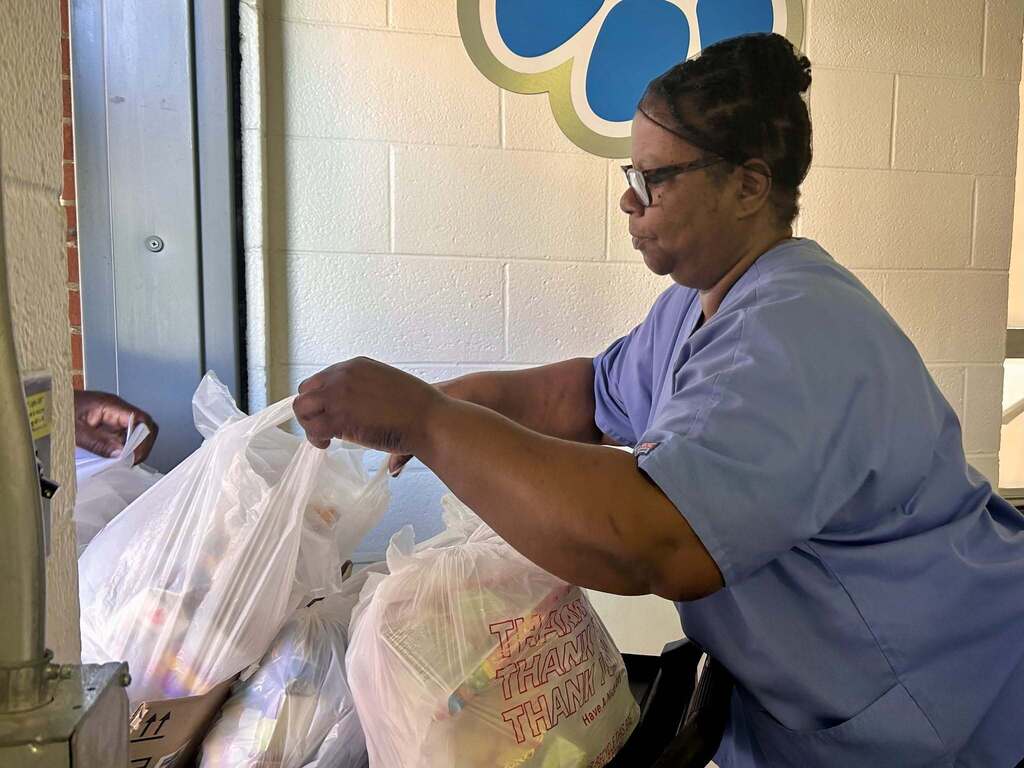 A child nutrition worker helps distribute food during the summer feeding program