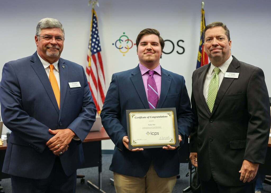 Three men stand to give an award