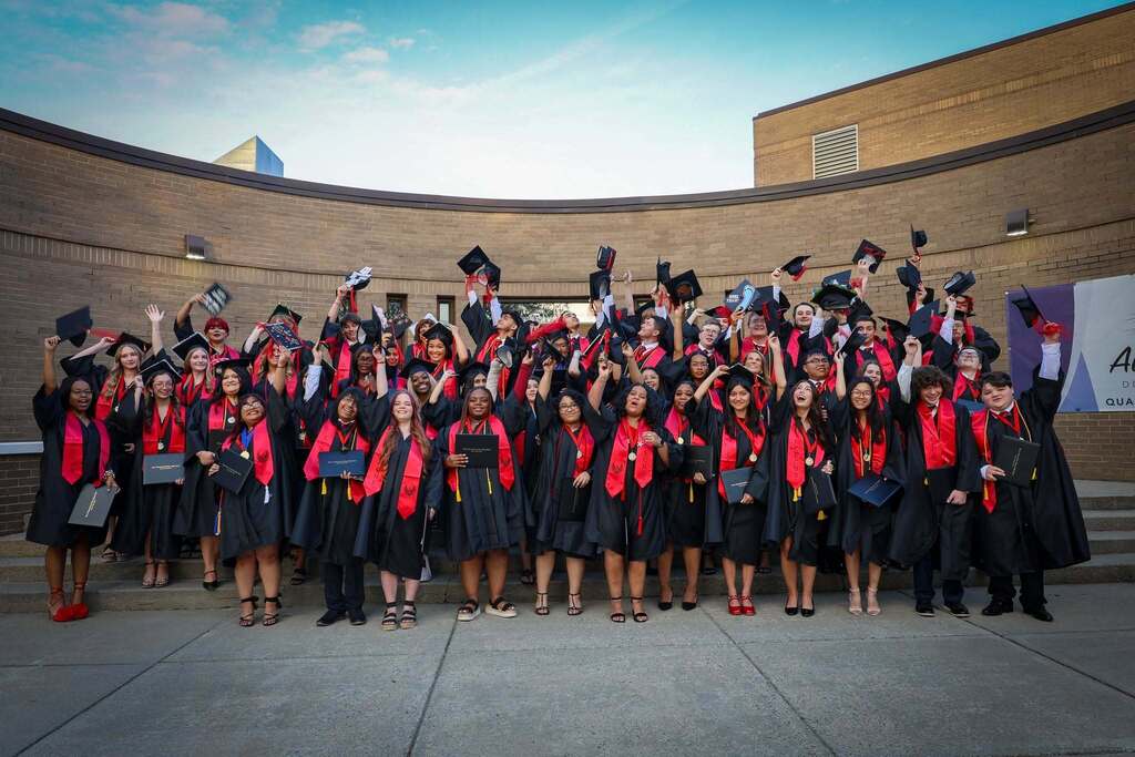 The students of early college stand after graduation