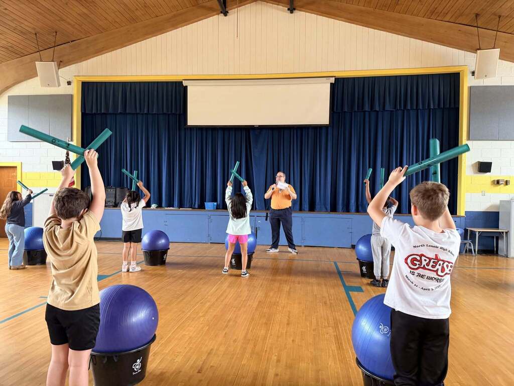 Students bang musical pipes together during gym class to learn and be active at the same time