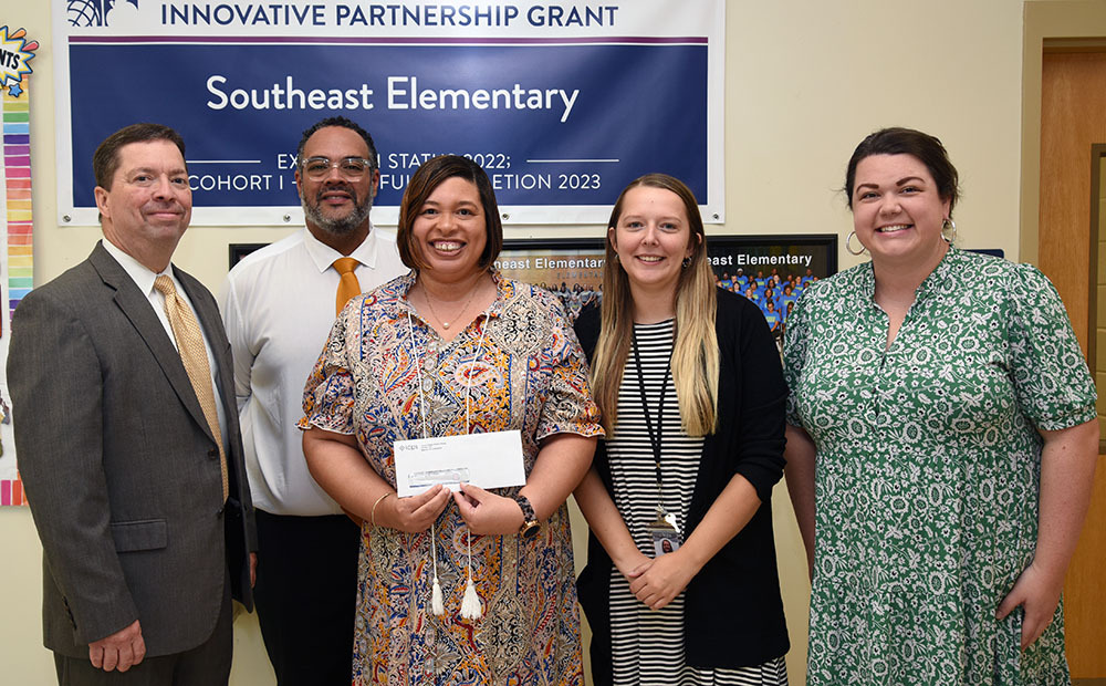 Five people pose with one holding a check.