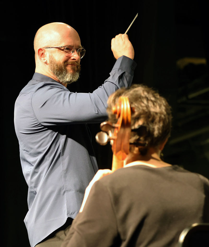Conductor leads the symphony with his baton.