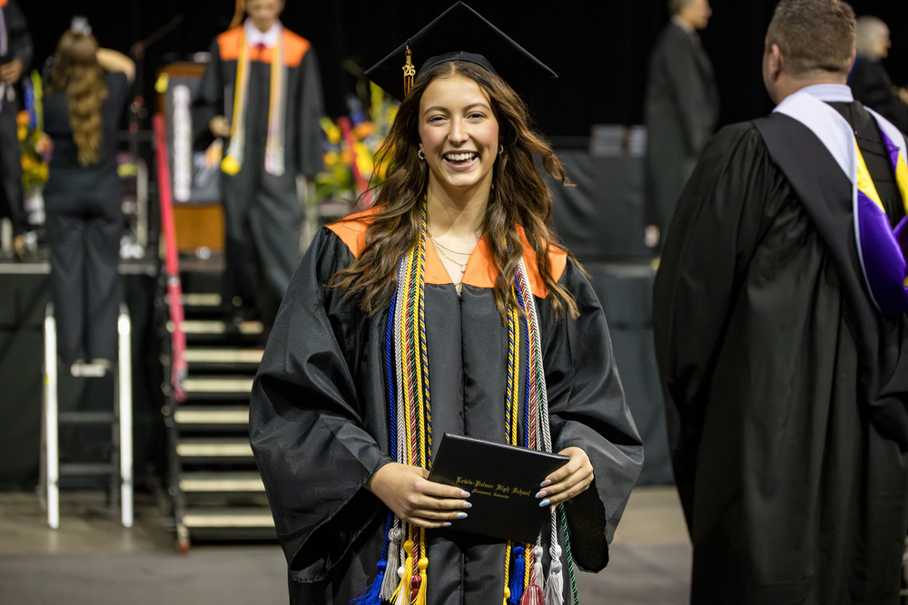 Female graduate in black gown with diploma.