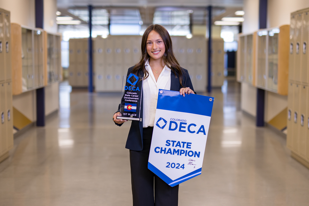 Claire Munroe holding her DECA State Champion trophy and pendant