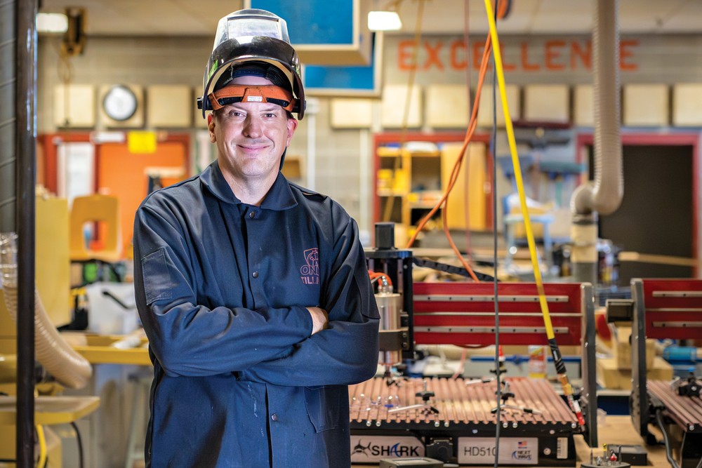 Andy Vrieze wearing a welding helmet while standing in the shop at LPHS