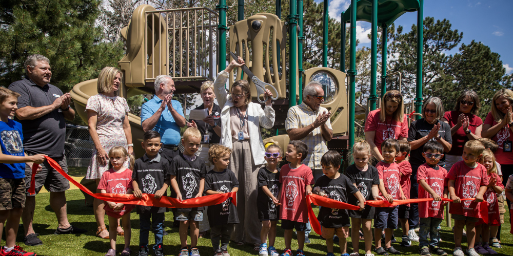 Ribbon cutting for new preschool program and playground at Palmer Lake Elementary School, students and D38 staff member clapping and celebrating after the ribbon was cut