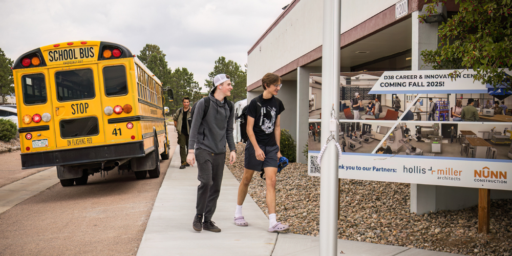Two male students walk into the Career and Innovation Center on the first day of classes, school bus