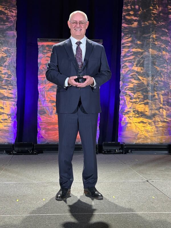 Brett Ridgway holding award on stage.
