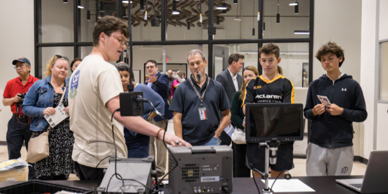 A CIC student explains some of the equipment to visitors