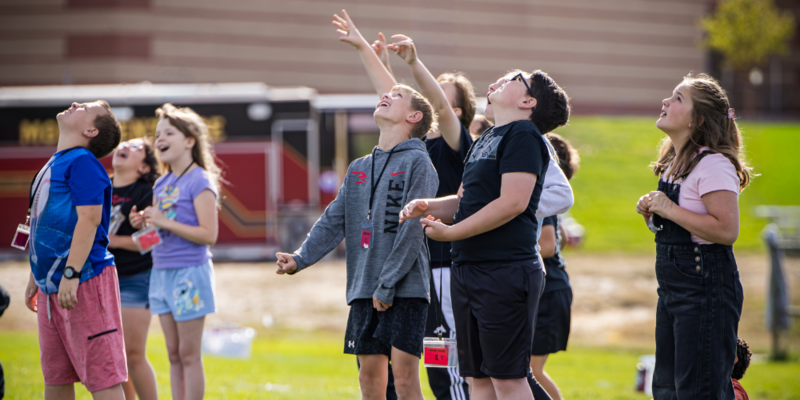 Students look up with fascination as they watch their rockets fly