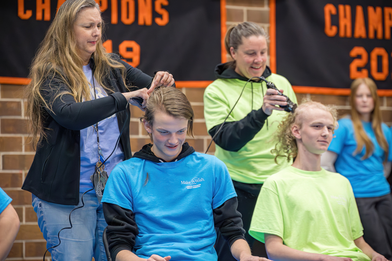 Two students getting their heads shaved to raise money