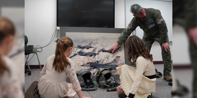 Students listen to a presentation from a military pilot