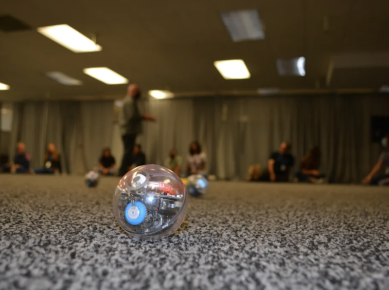 Ball shaped device on floor with students pictured in background