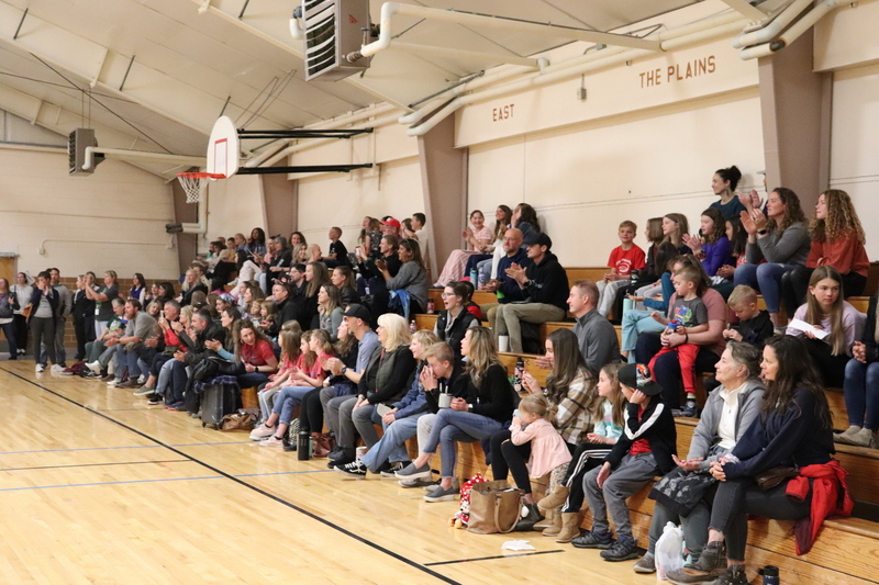 Parents and students sitting in the bleachers of school auditorium watching the tournament