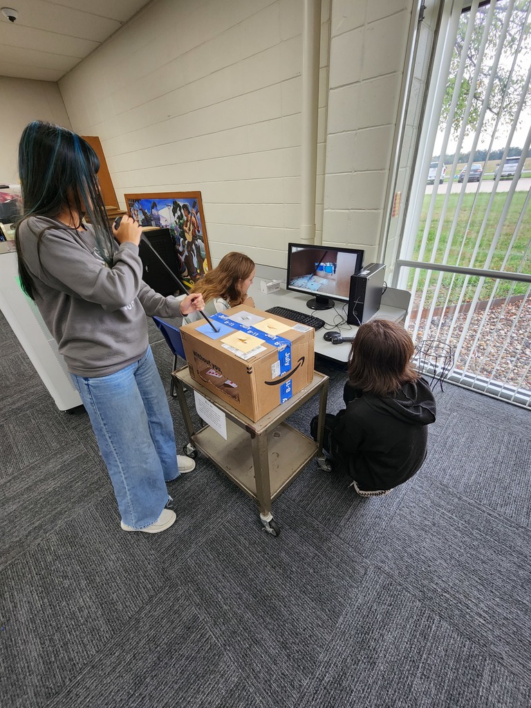 Students attempting to complete a task in a box using grabbers and a webcam