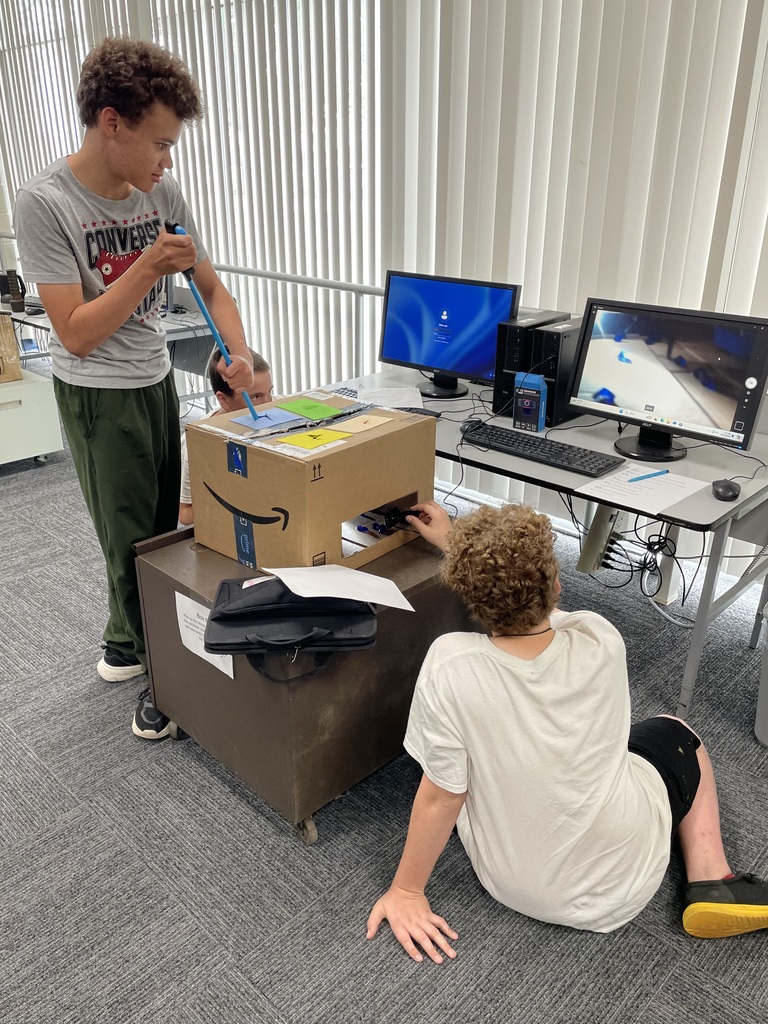 Students attempting to complete a task in a box using grabbers and a webcam