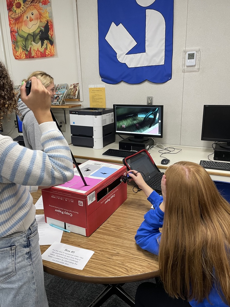 Students attempting to complete a task in a box using grabbers and a webcam