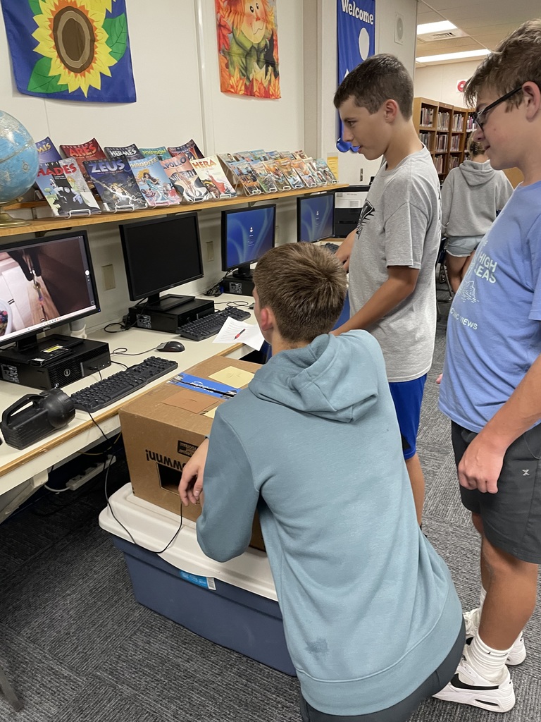 Students attempting to complete a task in a box using grabbers and a webcam