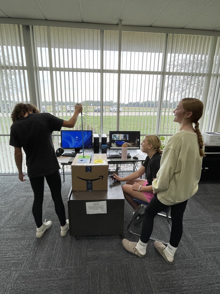 Students attempting to complete a task in a box using grabbers and a webcam