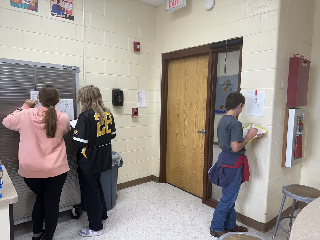 Students solving problems from posters hanging around the room