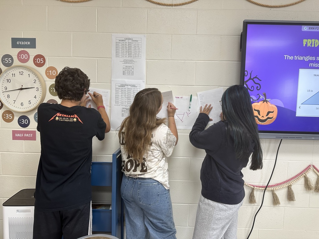 Students solving problems from posters hanging around the room
