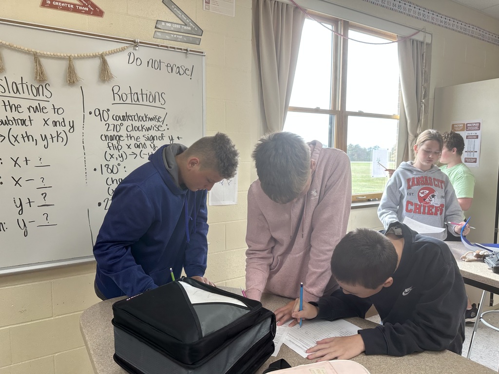 Students solving problems from posters hanging around the room