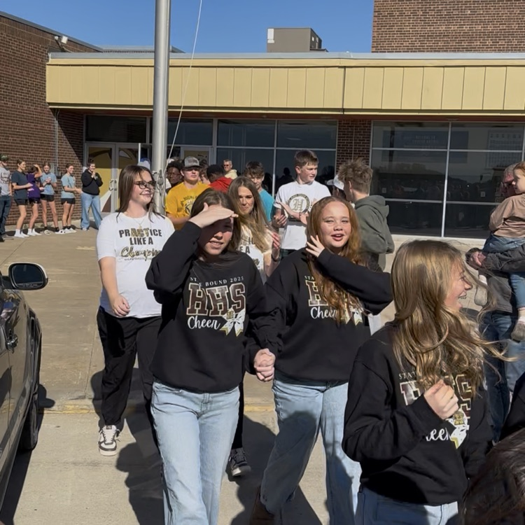 Highland Cheerleaders walking through a tunnel of support as they board the bus to head to the State Competition