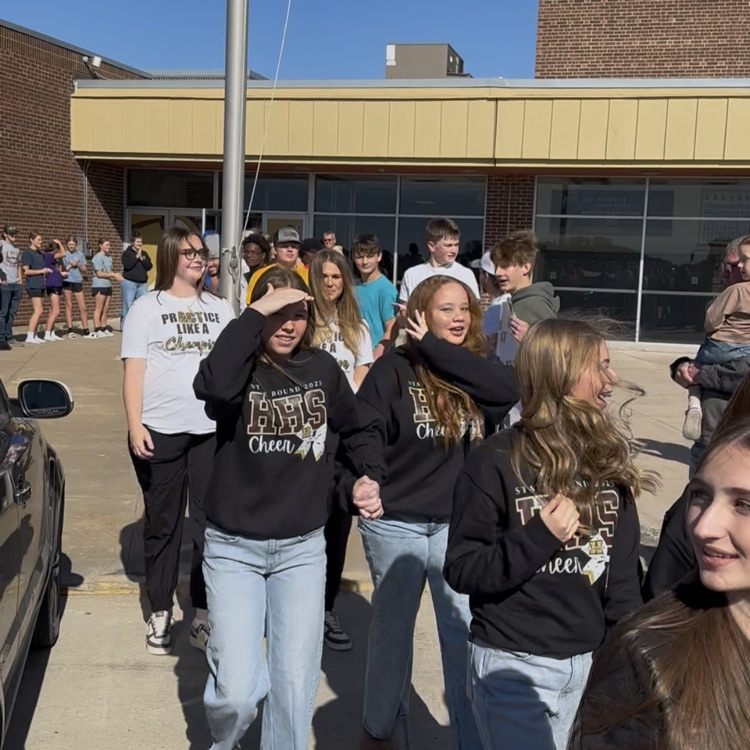 Highland Cheerleaders walking through a tunnel of support as they board the bus to head to the State Competition