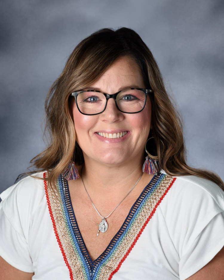 A smiling Mrs. Johnson wearing glasses in a white short sleave blouse with colorful collar.