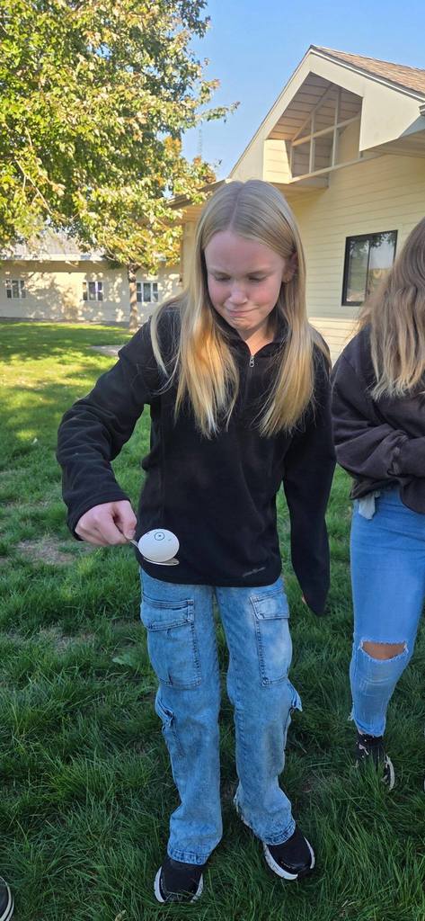students passing an egg with spoons