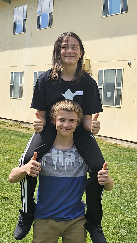 two students posing with their thumbs up
