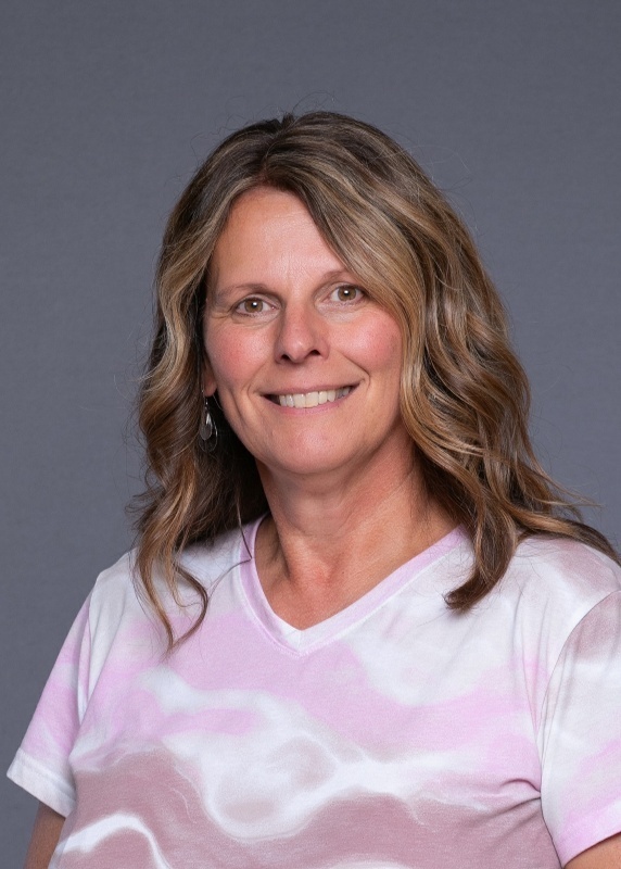 woman with brown shoulder length hair and a pink tie dye shirt on