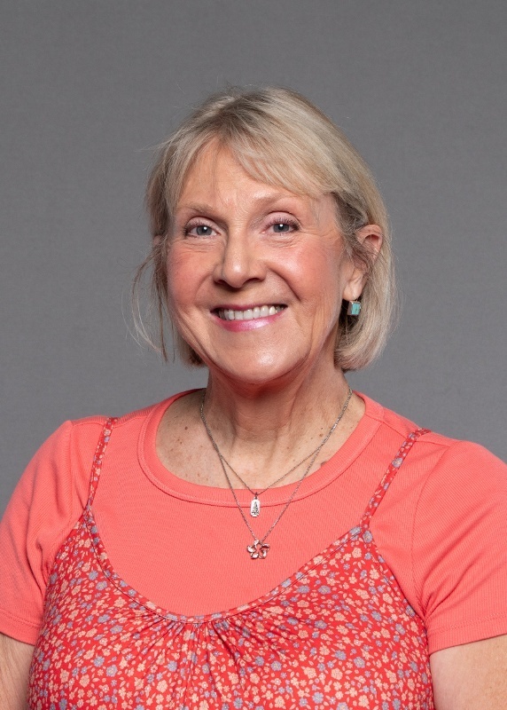 woman with short blonde hair and a coral colored shirt on