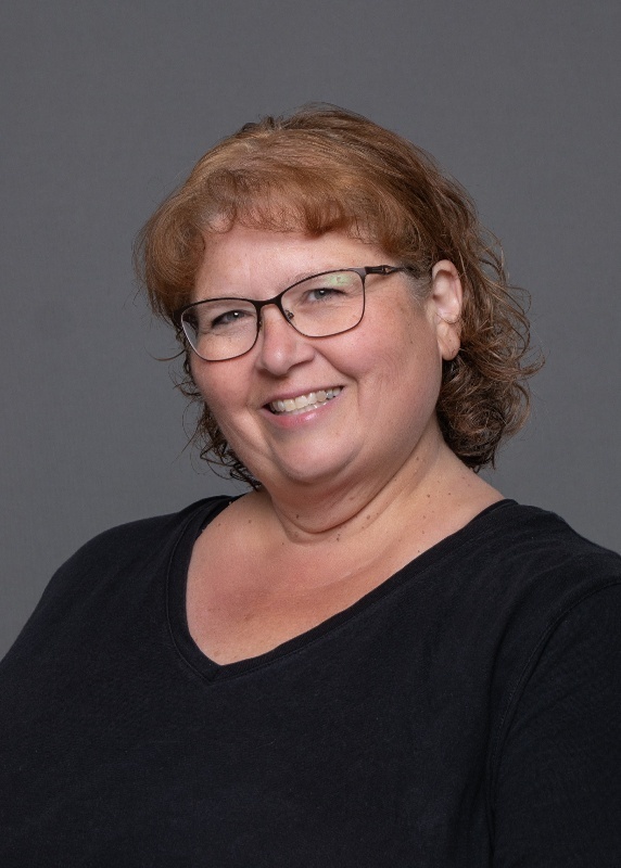 woman wearing a black shirt, glasses, and curly reddish brown hair