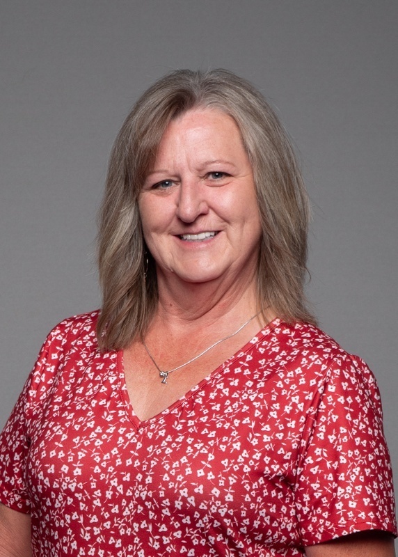 woman with shoulder length grey hair and a red top with white flowers on it