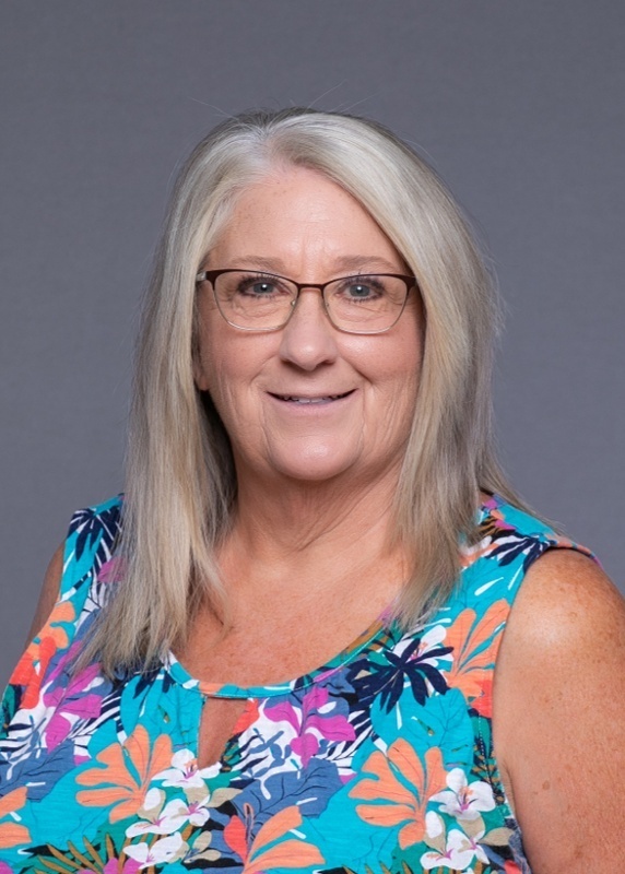woman with shoulder length hair, glasses, and a floral tank top on